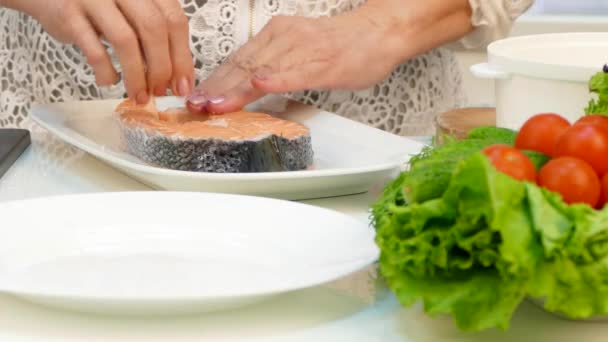 Een vrouw van zestig zouten biefstuk rode vis en plaatst een stuk van forel in een dubbele boiler. — Stockvideo