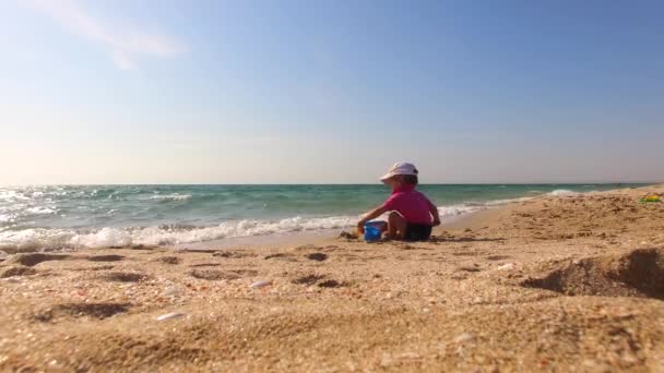 Kleine jongen spelen met zand op het strand — Stockvideo