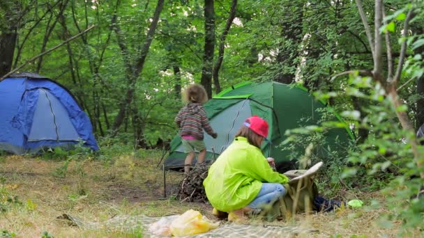 Twee kinderen spelen in de clearing in de buurt van de tenten in het bos. — Stockvideo