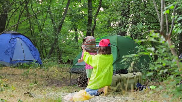 Dwoje dzieci grać na Polanie w pobliżu namiotów w lesie. — Wideo stockowe