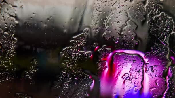 Tropfen und Wasserströme fließen bei Regen aus der Windschutzscheibe des Autos. — Stockvideo