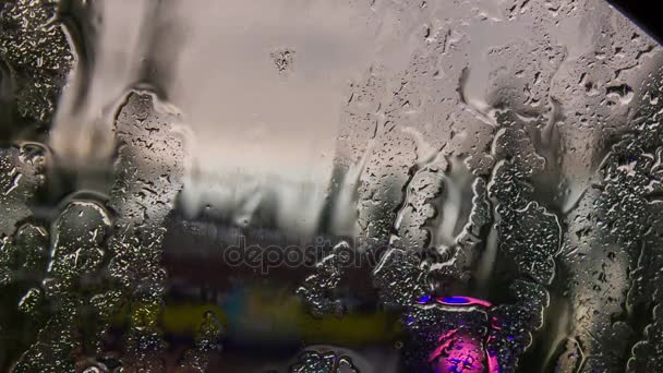 Gotas y corrientes de agua drenan del parabrisas del coche durante la lluvia . — Vídeo de stock