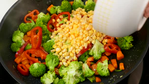 Giet maïs kernels in een koekenpan met gebakken groenten — Stockvideo