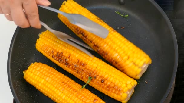 Turn the cooked corn cobs in a frying pan — Stock Video