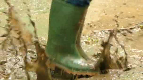 在橡胶靴子跳过肮脏的水坑 — 图库视频影像
