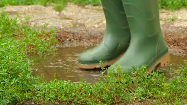 Pieds en bottes en caoutchouc amusant de sauter à travers la flaque d'eau — Video