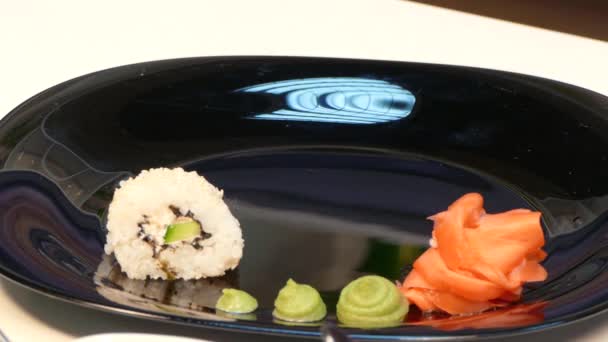 Руки кладут суши-рулеты на тарелку — стоковое видео