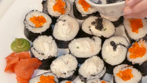 Decorate sushi rolls with black caviar — Stock Video