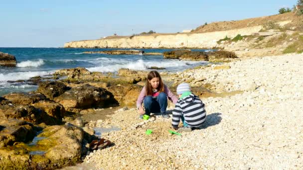 Chica y niño jugando en la arena en la playa . — Vídeos de Stock