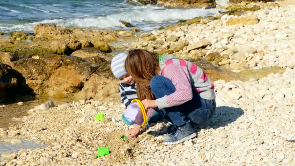 Una chica está jugando en la playa con un niño . — Vídeos de Stock