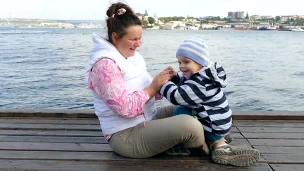 Une femme s'assoit sur le siège avant avec un enfant et joue . — Video