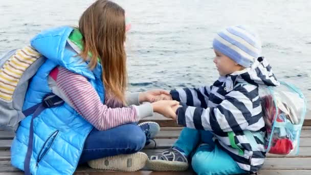 Una chica está jugando con un bebé en el muelle . — Vídeo de stock