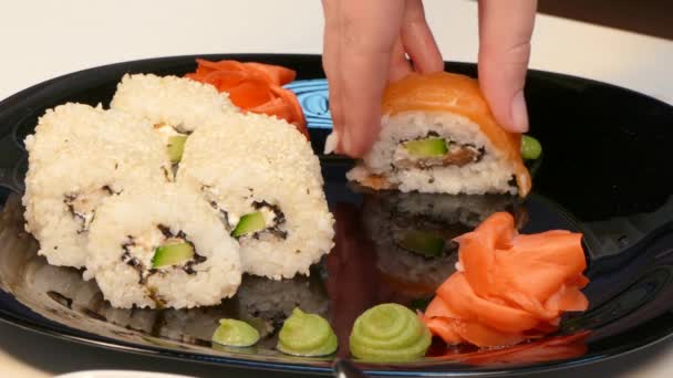 Un cuisinier fait un ensemble de rouleaux de sushi sur une assiette . — Video