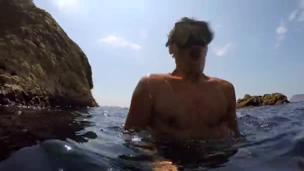 Mergulhador mergulha na água nada entre as rochas e flutua para cima e bate no barco — Vídeo de Stock