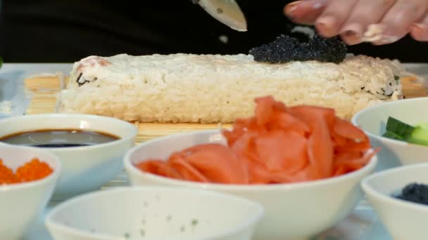 El cocinero espolvorea rollo de sushi con caviar negro . — Vídeo de stock