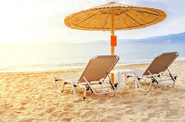 Güzel bir plaj ve güneş yakıcı ile okyanus gri saman şemsiye — Stok fotoğraf