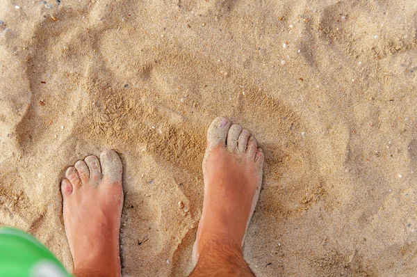 Homem fica no mar e olha para seu pé na areia e wate — Fotografia de Stock
