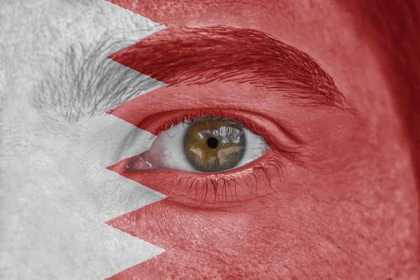 Human face and eye painted with flag of Bahrain — Stock Photo, Image