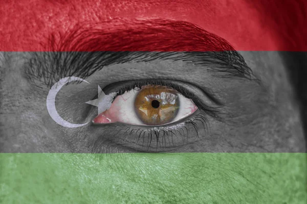 Human face and eye painted with flag of Libya