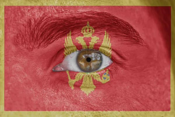 Human face and eye painted with flag of Montenegro — Stock Photo, Image