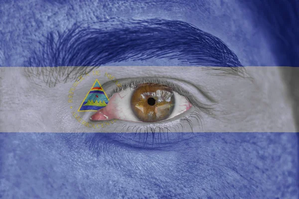 Emberi arc és a szem festett Nicaragua zászlaja — Stock Fotó