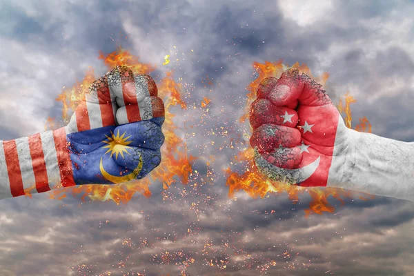 Zwei Fäuste mit der Flagge von Malaysia und Singapore stehen sich zum Kampf gegenüber — Stockfoto