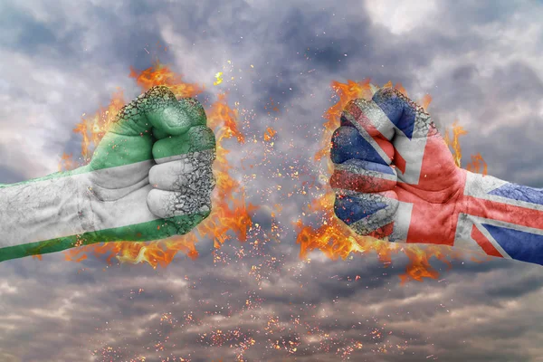 Два кулак з прапор Нігерії і Великої Британії стикаються один на одного готові до боротьби — стокове фото