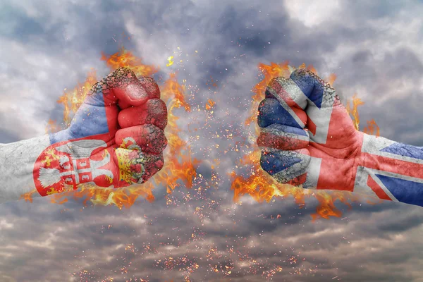Два кулак з прапор Сербії та Великої Британії стикаються один на одного готові до боротьби — стокове фото
