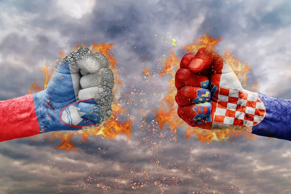 Zwei Fäuste mit der slowenischen und kroatischen Flagge stehen einander kampfbereit gegenüber — Stockfoto