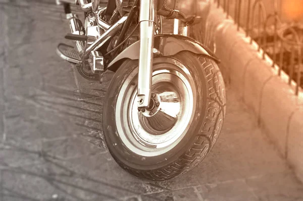 Чорно-білий мотоцикл перше колесо, припарковане на міській вулиці з палаючим сонцем на ньому — стокове фото