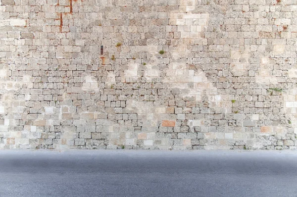 Bloquear parede de cimento com estrada em primeiro plano asfalto sujo à frente — Fotografia de Stock