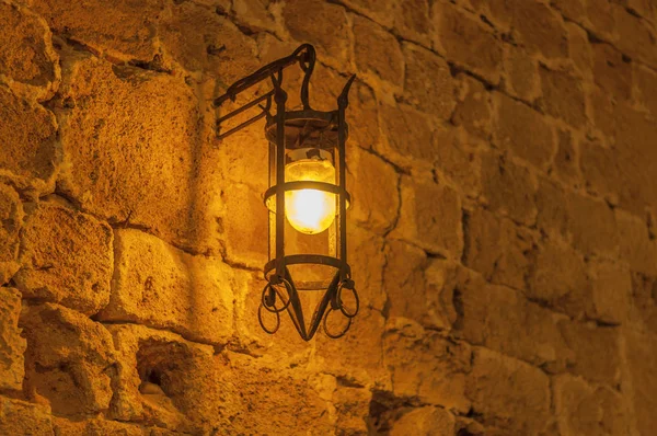 Close old light at night hanging on a medieval street fortress wall — Stock Photo, Image