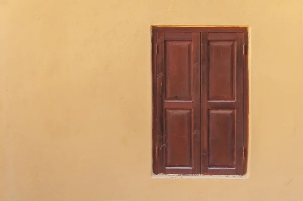 Vista próxima da janela de madeira vermelha escura fechada moderna na parede da casa texturizada de cimento amarelo — Fotografia de Stock