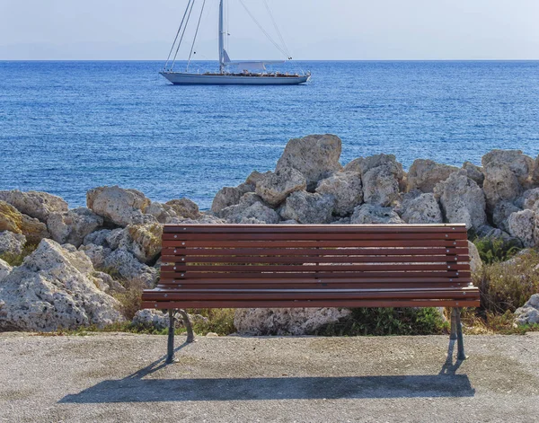 Banco de madera vacío en el muelle del barco con hermoso mar azul y barco atracado en el fondo —  Fotos de Stock