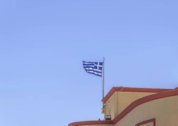Bandeira grega acenando no prédio com céu azul limpo no dia de verão — Fotografia de Stock