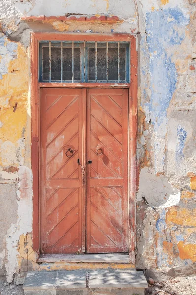 Porta de madeira vermelha escura fechada moderna na parede da casa texturizada de cimento amarelo — Fotografia de Stock