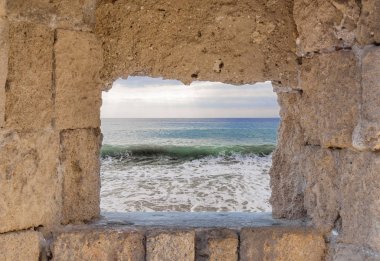 Mavi sahil dalga ile bulutlu ska ile eski ortaçağ kalesi çerçeve penceresi