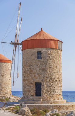 Mavi bulutlu gökyüzü ve arka planda deniz kıyısında eski yel değirmeni