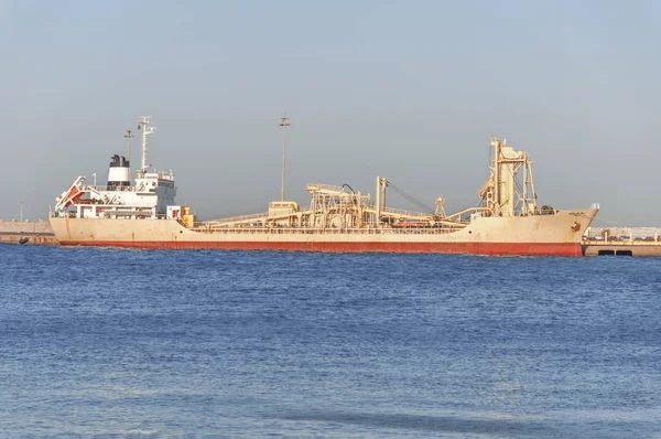 Old metal Ship with red bottom on blue sea at dock with clean sky — Stock Photo, Image