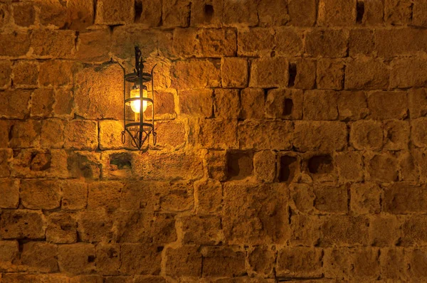 Bir ortaçağ sokak Kalesi duvar arka plan üzerinde asılı gece eski ışık lamba