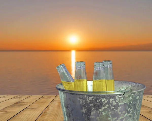 Erfrischungsgetränk von vier Flaschen im Eimer auf Holzterrasse und Sonnenuntergang Hintergrund — Stockfoto