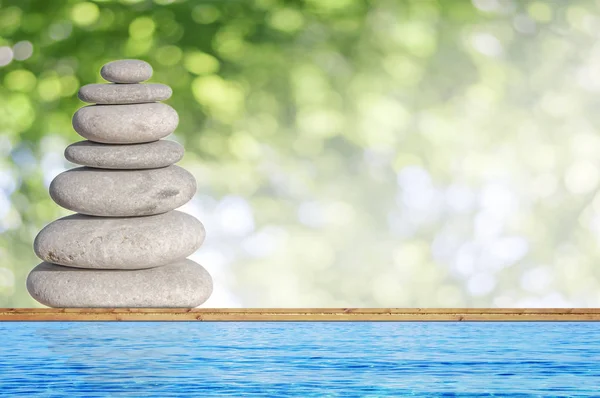 Diversi piccola pietra spiaggia come simbolo di equilibrio su legno con sfondo verde bokeh — Foto Stock