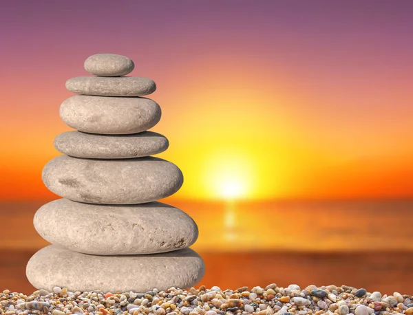 Liten strand zen stone med solen ner bakgrunden nära upp för spa och balans symbol — Stockfoto