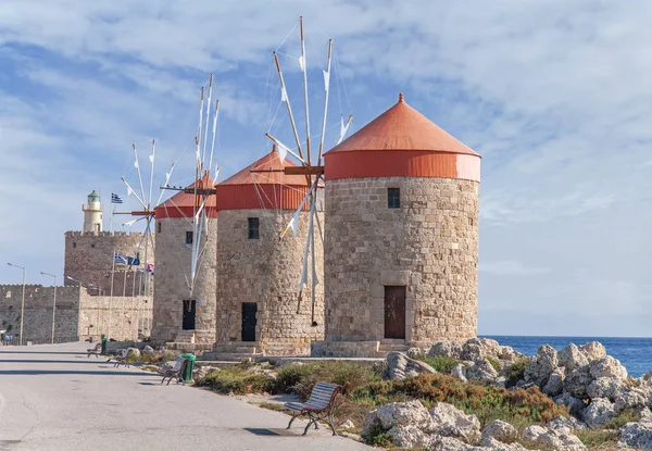 Üç eski fırıldak kenarı mavi bulutlu skay ve arka planda deniz feneri ile