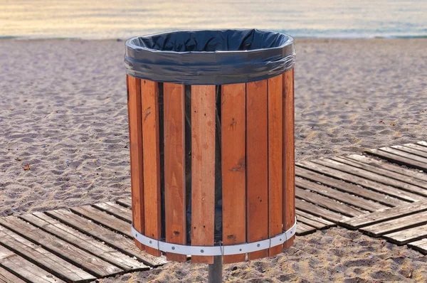 Wooden garbage can for rubbish on a sandy beach on a summer day