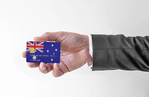 Banco tarjeta de crédito de plástico con la bandera de Australia la celebración del hombre en traje elegante —  Fotos de Stock