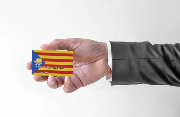 Tarjeta de crédito bancaria de plástico con bandera de Cataluña que sostiene al hombre en traje elegante — Foto de Stock