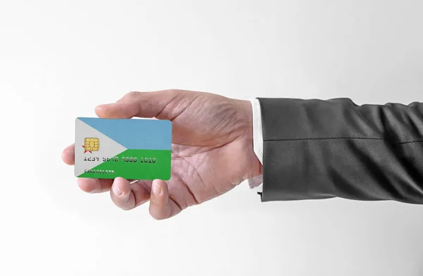Bankovní kreditní plastová karta s vlajkou Džibuti držení muž v elegantním obleku — Stock fotografie