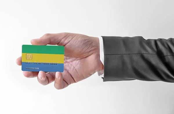 Bankovní kreditní plastová karta s vlajkou Gabonu drží muže v elegantním obleku — Stock fotografie