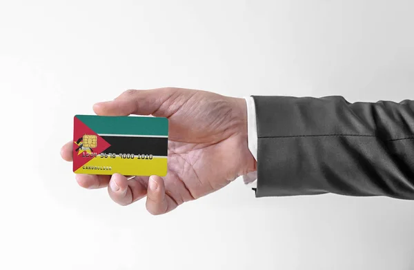 Bankovní kreditní plastová karta s vlajkou Mosambiku držení muž v elegantním obleku — Stock fotografie